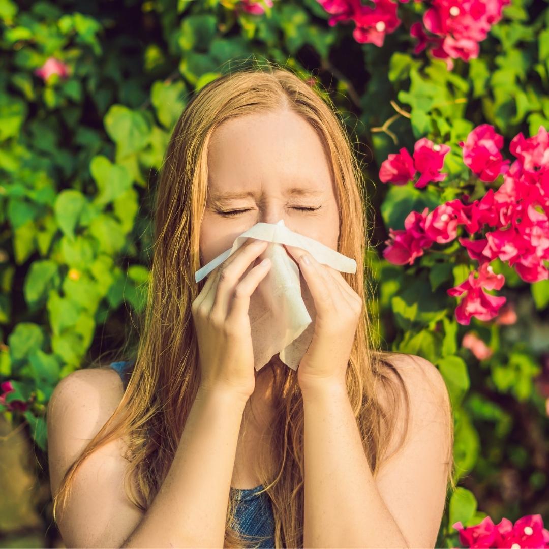Woman with allergies sneezing into a tissue 