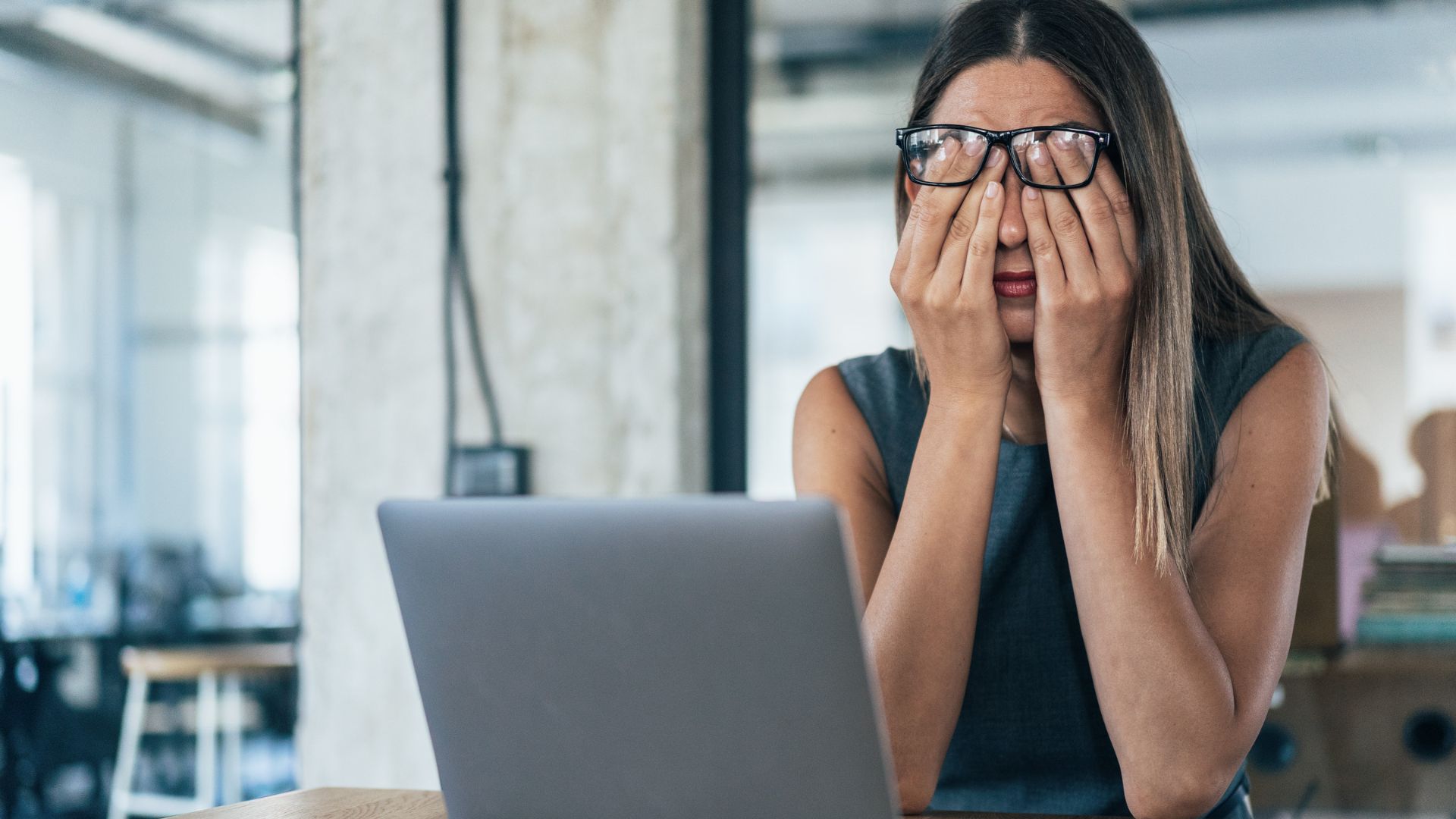 Person rubbing their eyes while using a laptop