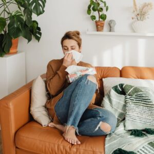 Person using a tissue while sitting on a couch