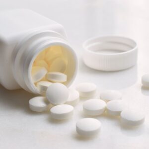 Bottle of white pills spilling out onto a countertop